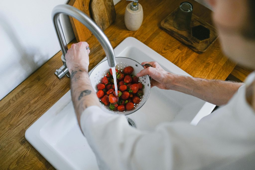 man washing berries in kitchen sink